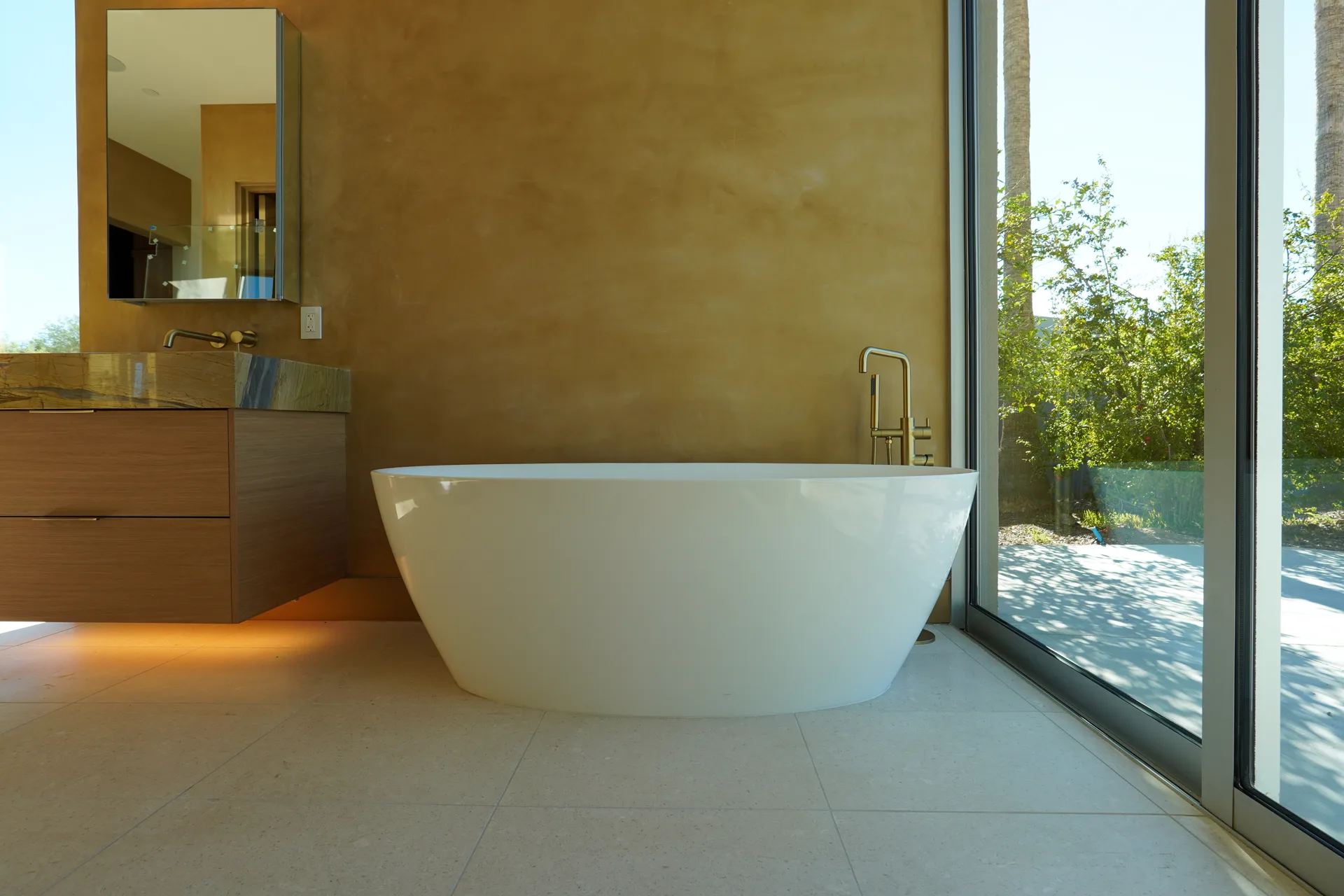 Freestanding tub beside full-height glass in the primary bath