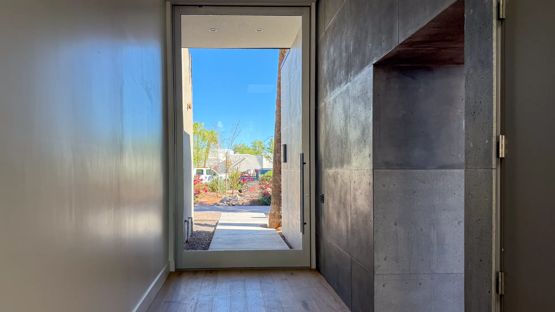 Glass pivot entry door framed by board-formed concrete walls