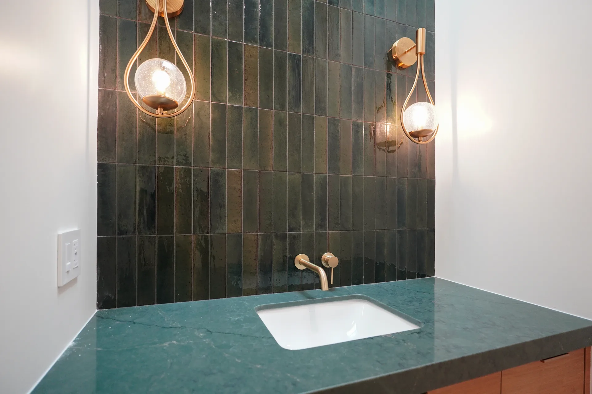 Powder room counter with wall-mounted brass faucet