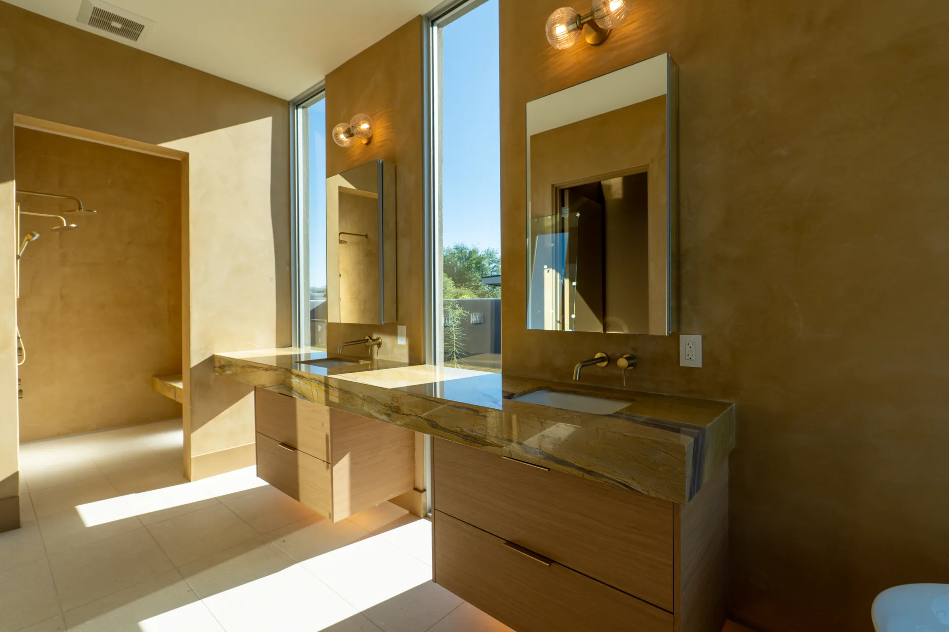 Primary vanity with stone countertop and brass sconces
