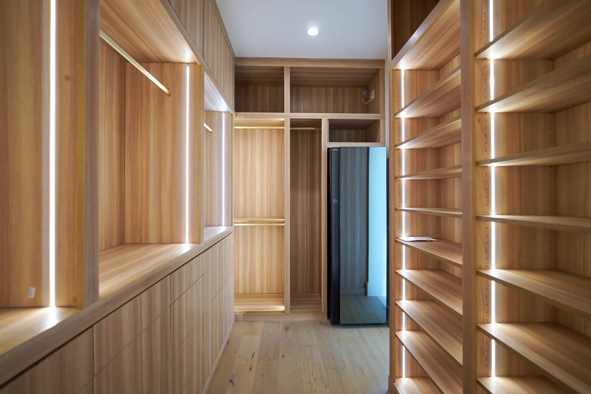 Primary walk-in closet with lit wood shelving