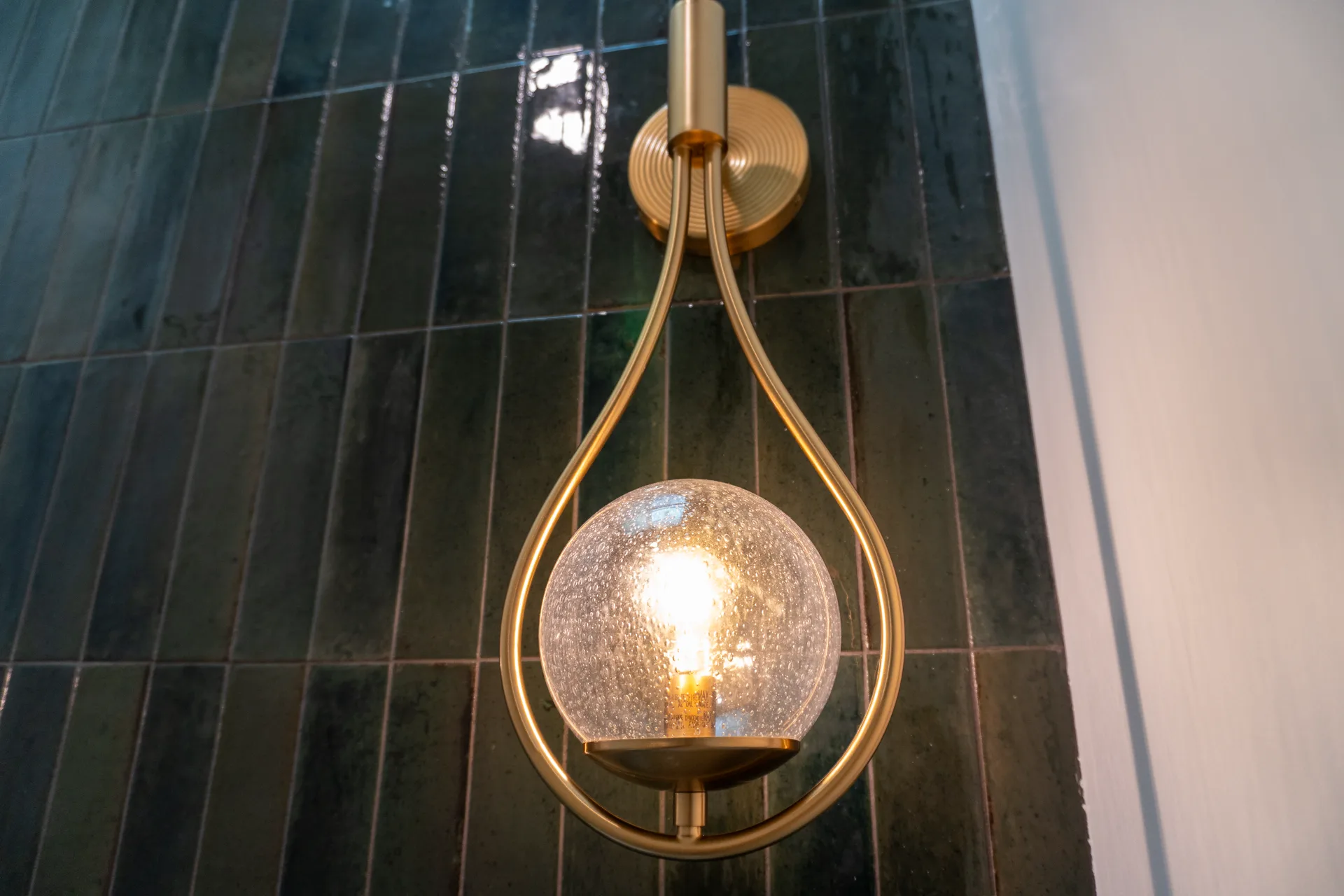 Brass and seeded glass sconce on green tile